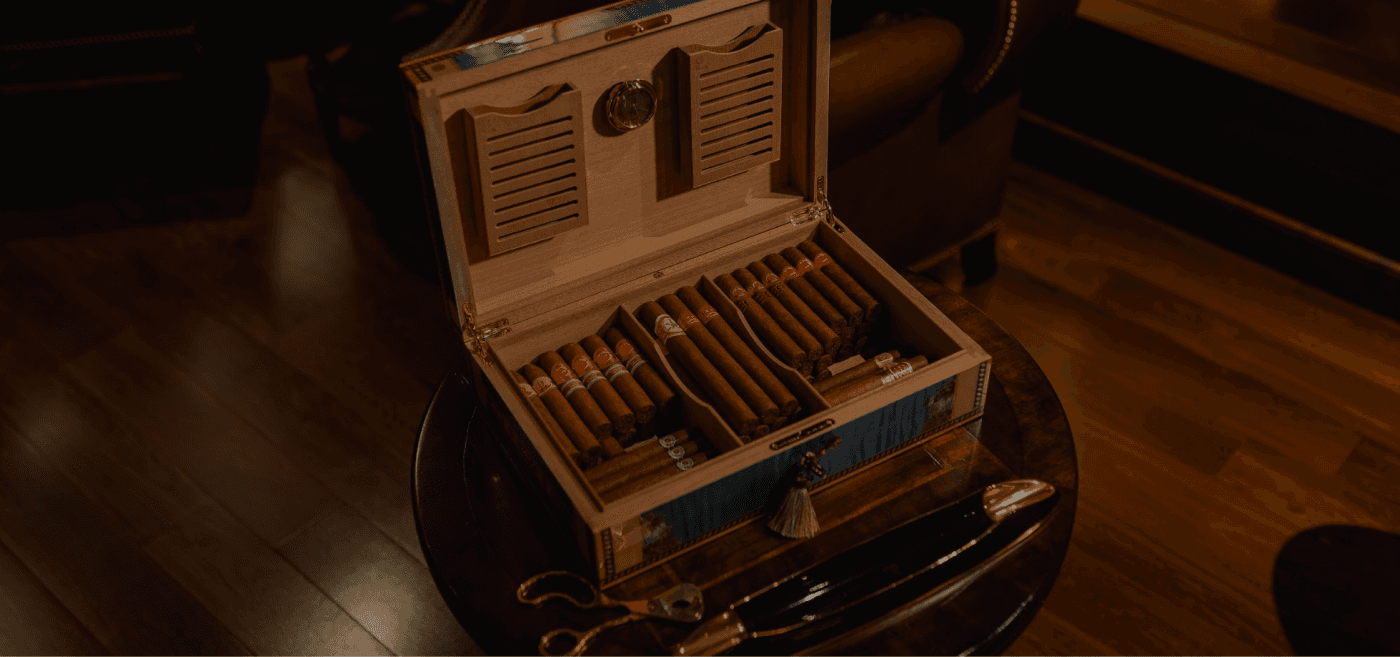 An open humidor of premium cigars in an amber-lit lounge